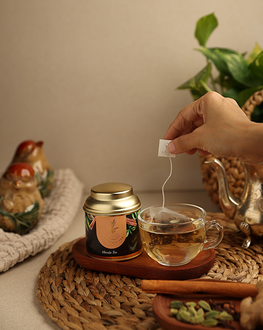 A hand making Pekoe Masala Tea from tea bag in a glass cup